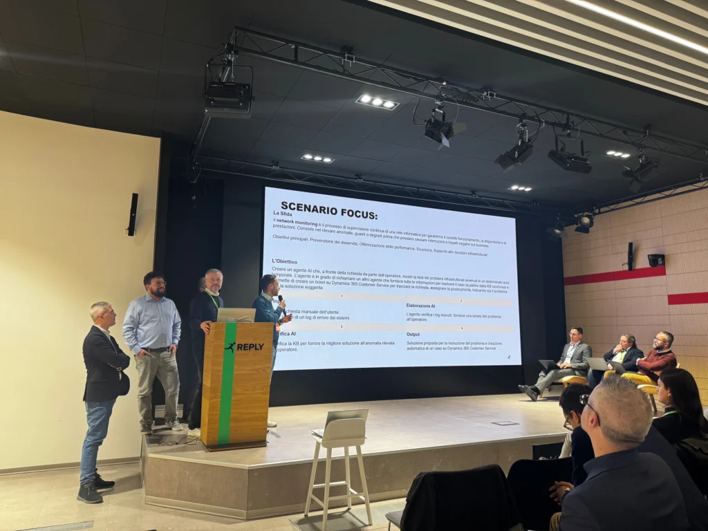 A group of professionals is presenting on stage to an audience. A large screen displays "Scenario Focus" with bullet points. The atmosphere is formal and focused.