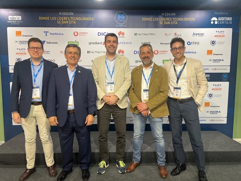 Group of five professionals posing at a technology event, showcasing collaboration and innovation in the tech industry.