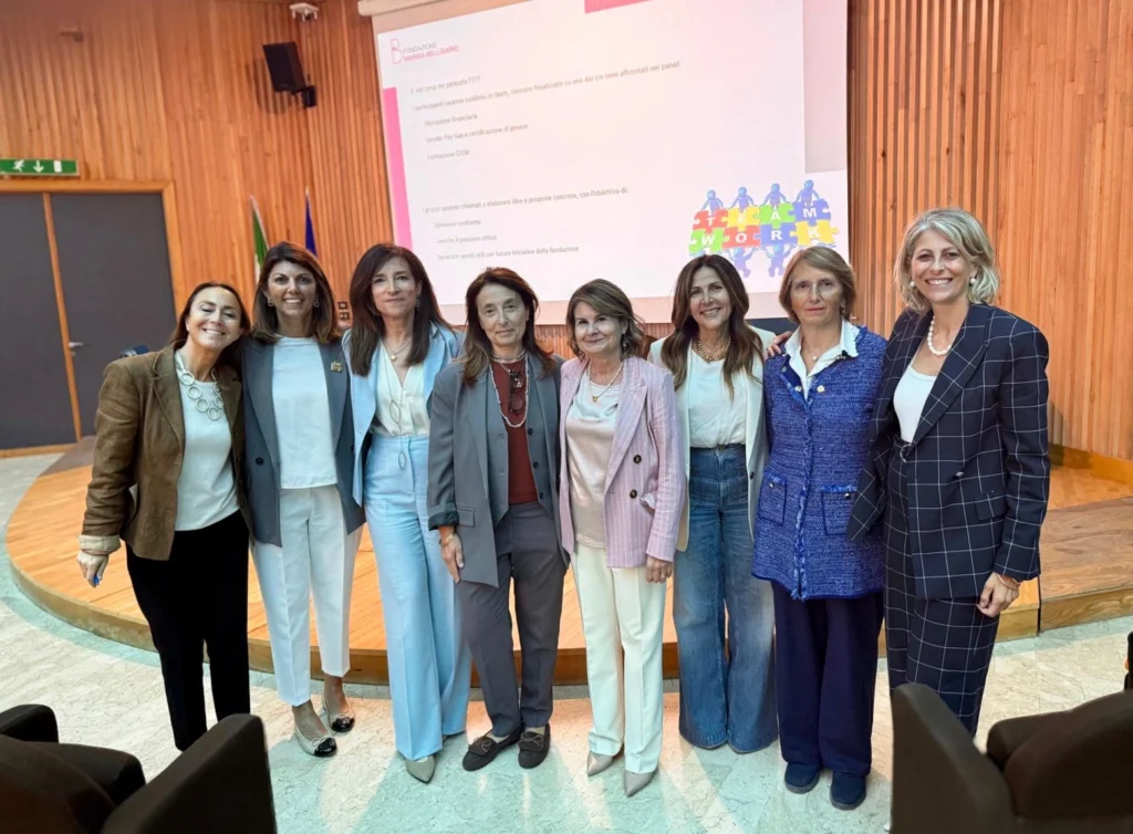 A group of eight professional women posing together at a conference, showcasing empowerment and collaboration in a formal setting.